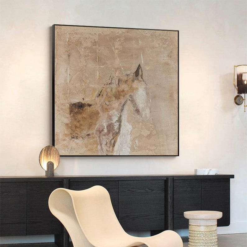 May include: Abstract painting of a horse's head in shades of brown, beige, and white. The painting is framed in a black frame and hangs on a white wall.