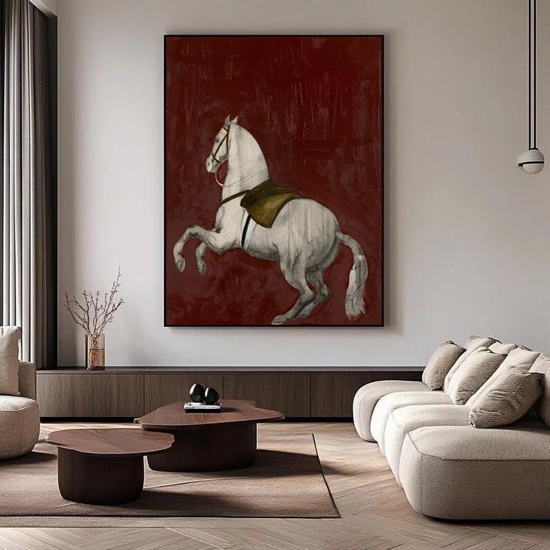 May include: A framed artwork featuring a white horse rearing up against a deep red background. The horse has a saddle and bridle, and the artwork is displayed in a modern living room setting.