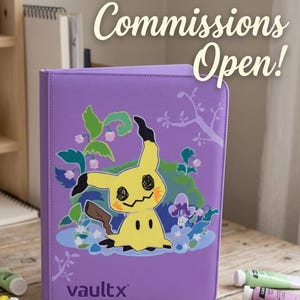 Pode incluir: Um fichário roxo com um gráfico do personagem amarelo Mimikyu cercado por folhagem verde e flores azuis. O texto Commissions Open! está impresso em branco acima do fichário e o logotipo Vaultx está impresso no canto inferior esquerdo.