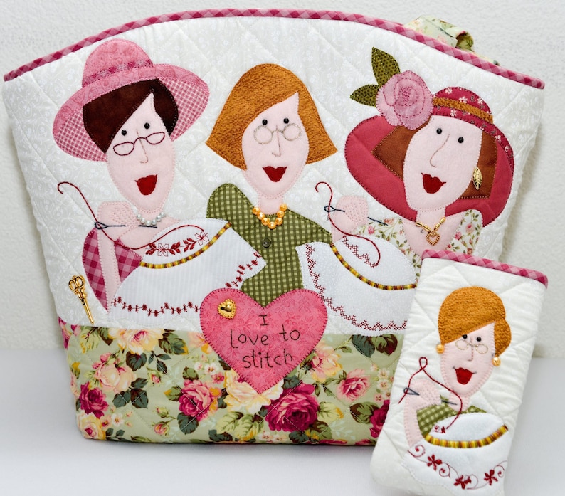 Puede incluir: Una bolsa de mano acolchada con estampado floral y tres figuras bordadas de mujeres que sostienen agujas e hilo. La bolsa tiene un parche en forma de coraz&oacute;n con el texto "Me encanta coser".