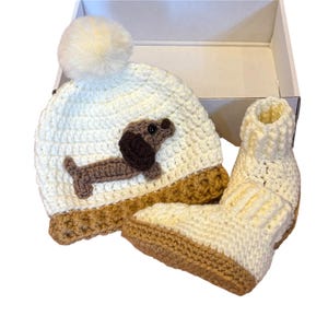 Crochet dachshund baby hat and booties set in cream with pom pom gift boxed newborn outfit