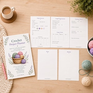 Peut inclure: Un planificateur de projet de crochet avec des pages pour les détails du projet, les notes et les croquis. La couverture présente un panier de pelotes de laine colorées. Une tasse de café et de la laine sont également visibles.