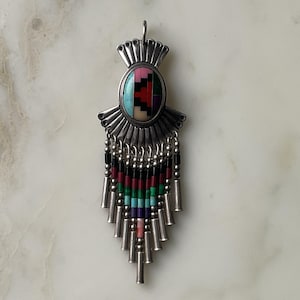 May include: A silver pendant featuring an oval mosaic design in pink, black, red, and turquoise. Below the central design are rows of colourful beads in black, red, green, blue, purple, and pink, with silver tubes at the base.