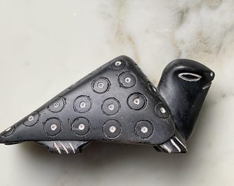 May include: A carved black turtle figurine with a triangular shell decorated with white-filled circles. The turtle's head is smooth, and the feet have white accents. This decorative item is likely a home decor piece.