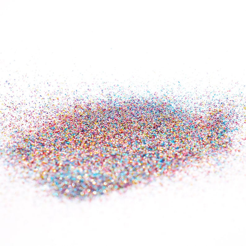 May include: A pile of colorful glitter on a white background. The glitter is a mix of red, blue, green, gold, and silver.