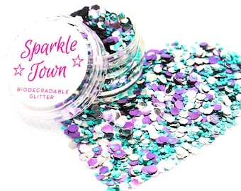 May include: A small clear jar filled with teal, purple, silver, and black glitter. The jar has a white label that says "Sparkle Town" with two stars and "Biodegradable Glitter".