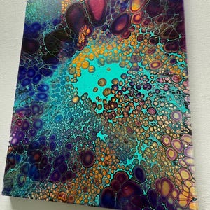 May include: Abstract painting with a teal, purple and gold colour scheme. The painting features a circular pattern of small and large circles.