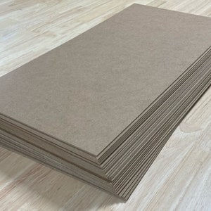 May include: A stack of brown cardboard sheets, likely for crafting or other DIY projects.