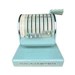 May include: A vintage, mint-green Paymaster cash register. The register features a series of numbered keys, dollar and cent symbols, and a handle. The word "PROTECTION" is printed vertically on the side. The base of the register has the word "PAYMASTER" printed on it.