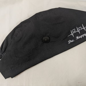 May include: Black scrub hat with a white embroidered heartbeat design and the text "Dre. Happy Teeth".