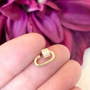 May include: Gold-toned metal clasp with clear cubic zirconia stones. The clasp is in the shape of a carabiner.