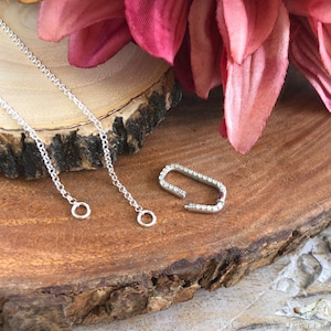 Collar con cierre de plata de ley con circonita cúbica, colgante con dije, mosquetón con cierre a presión oblongo, cierre con realce de circonita cúbica y eslabón de circonita cúbica.