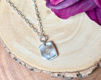 May include: A silver necklace with a small, rectangular pendant featuring a star-shaped design with clear crystals.