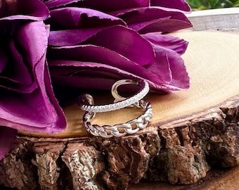 Könnte beinhalten: Ein silberner Ring mit einem Doppelband-Design. Das obere Band ist ein dünnes Band mit kleinen, klaren Steinen. Das untere Band ist ein dickeres Kettengliedband.