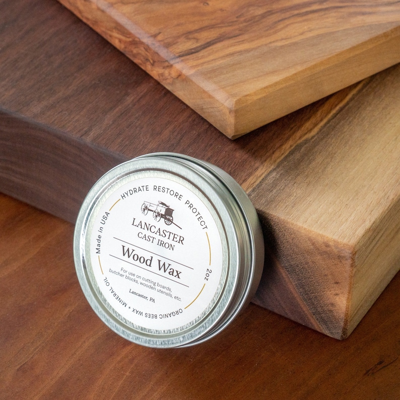 May include: A silver tin of Lancaster Cast Iron Wood Wax, a 2 ounce container with a label that reads "Hydrate Restore Protect" and "Organic Bees Wax - Mineral Oil".
