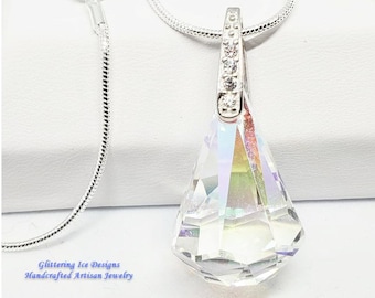 May include: A silver chain necklace with a teardrop-shaped crystal pendant. The crystal is iridescent and has a faceted design. The pendant is attached to the chain with a silver bail.