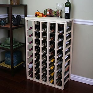 May include: A wooden wine rack with 72 bottle slots. The rack is made of natural wood and has a light brown finish. The rack is standing on a wooden floor.