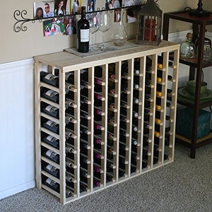 May include: A wooden wine rack with multiple shelves, holding rows of wine bottles. The rack is made of light wood and has a natural finish. The rack is freestanding and has a rectangular shape.