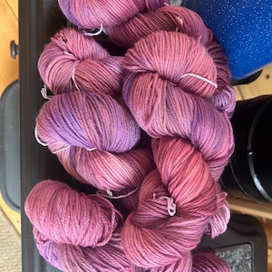 Könnte beinhalten: Eine Garnrolle in Rosatönen und Lila. Das Garn ist weich und flauschig und perfekt zum Stricken oder Häkeln.