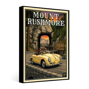 May include: A framed art print featuring a vintage car driving towards Mount Rushmore. The artwork has a retro travel poster style, with the words "Mount Rushmore" at the top. The car is yellow, and the background includes a tunnel and a sign that reads "Black Hills Tour."