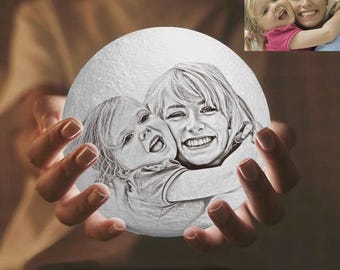 May include: A white, spherical lamp with a detailed engraved image of a woman and a child embracing. The lamp is held in cupped hands, with a small color photo of the same subjects in the upper right corner.
