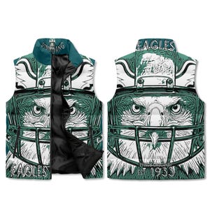 May include: A reversible vest featuring a detailed eagle design with a football helmet. The vest is primarily white and green, with the word "EAGLES" prominently displayed. The vest has a black zipper and collar.