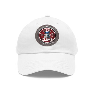 Peut inclure: Casquette de baseball blanche avec un écusson circulaire représentant une chèvre portant des lunettes de soleil. L'écusson indique "Climb Like A Mountain Goat" et "Keep on Grinding". La casquette a une visière incurvée et un bouton sur le dessus.
