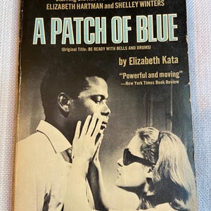 May include: A vintage paperback book titled A Patch of Blue by Elizabeth Kata. The black and white cover features a photograph of a person touching the face of another person wearing dark sunglasses. Text includes movie cast details and reviews.