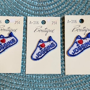 May include: Three patches with a white running shoe design, a red heart, and the words "I JOGGING" in blue. Each patch is on a small cream-colored card with the word "Boutique" and the price 75¢.