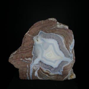 Könnte beinhalten: Eine große, unregelmäßig geformte Achat-Geode mit einem weißen und hellblauen Inneren. Das Äußere ist braun und beige mit einem geschichteten Muster.