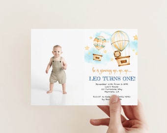 May include: A blue and yellow hot air balloon birthday invitation with a watercolor design. The invitation features a baby boy in a brown jumpsuit and a lion in a hot air balloon. The text reads "He is growing up, up, up... Leo Turns One!" with details for the party.