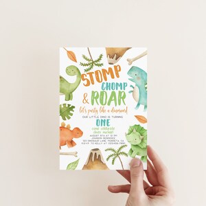 May include: A dinosaur-themed birthday party invitation with a green, orange, and blue dinosaur illustration. The text reads "Stomp, Chomp & Roar! Let's party like a dinosaur! Our little dino is turning one. Come celebrate [name] August 8th at 12 pm Johnson Residence 123 Dinosaur Lane, [city], CA RSVP to Kelly at [phone number]"