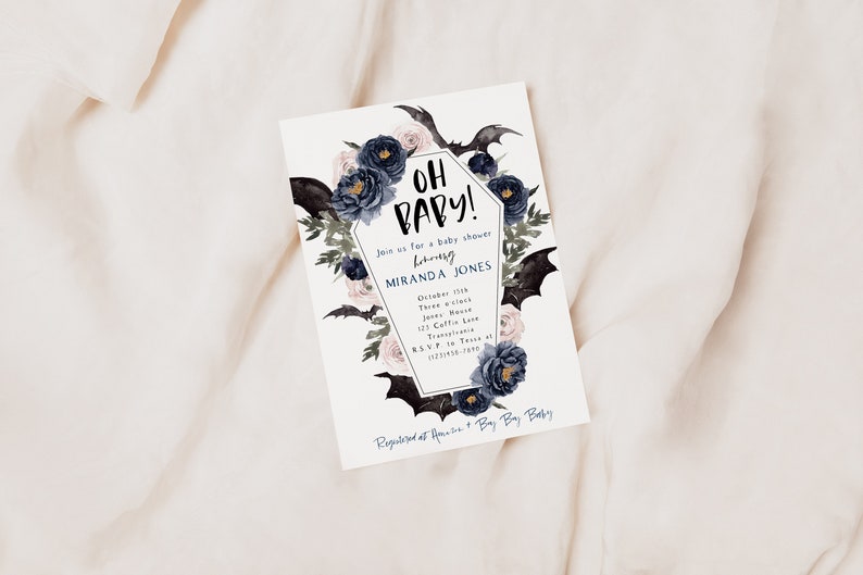 May include: A white baby shower invitation with a black coffin-shaped frame decorated with black bats, blue and pink flowers, and the text "Oh Baby!"  Join us for a baby shower honoring Miranda Jones.  October 11th, Three o'clock, Jones House, 123 Coffee Lane, Transylvania. RSVP to Tessa at (123) 456-7890.  Registered at Amazon + Buy Buy Baby.