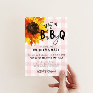 May include: Pink and white gingham baby shower invitation with a sunflower illustration. The text reads "It's a BaByQ honoring Kristen & Mark, Saturday August 8 | 4:00 PM, Join us for BBQ, Beer & Baby Talk, The Johnson's Backyard, 125 Turnstone Lane | Murrieta, CA, RSVP to Kelly at (123)456-7890, registered at Amazon.com".