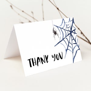 May include: A white thank you card with a black spider and blue spider web illustration. The text "THANK YOU" is written in black.