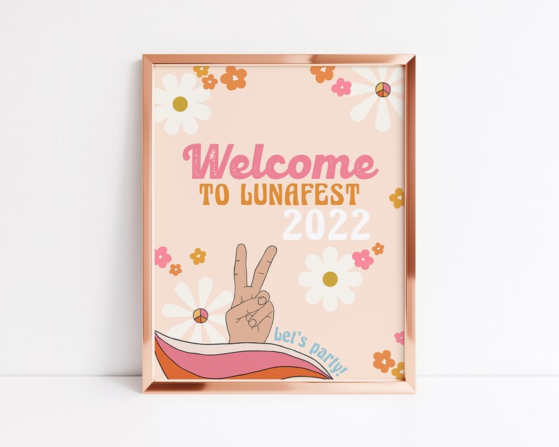 Peut inclure: Une pancarte d'accueil rose et orange avec un signe de paix et des fleurs. La pancarte indique "Bienvenue &agrave; LunaFest 2022" et "Let's Party !"