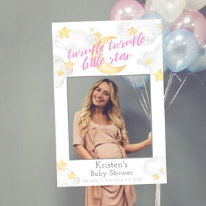 Puede incluir: Un accesorio de fotomatón blanco con un diseño de luna y estrellas rosa y amarillo. El texto "twinkle twinkle little star" está escrito en rosa. El texto "Kristen's Baby Shower Saturday, February 4, 2022" está escrito en la parte inferior.