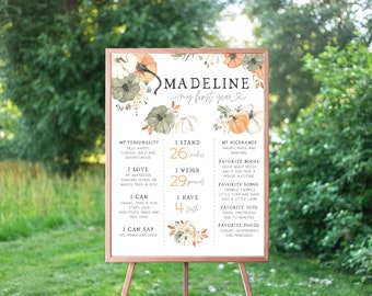 May include: A printable first birthday milestone poster with a fall theme. The poster features a watercolor illustration of pumpkins and flowers in shades of orange, green, and white. The poster includes the name Madeline and details about her first year, including her height, weight, and favorite things.
