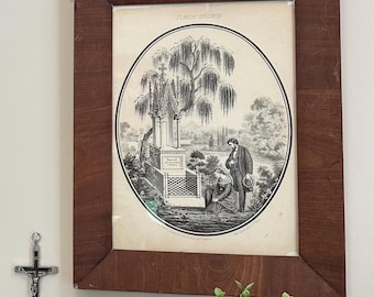 Puede incluir: Una impresión enmarcada antigua con una ilustración en blanco y negro de un sauce llorón, una lápida y dos figuras. El marco es marrón oscuro. Un crucifijo plateado cuelga de la pared a la izquierda. Una planta verde está en la parte inferior.