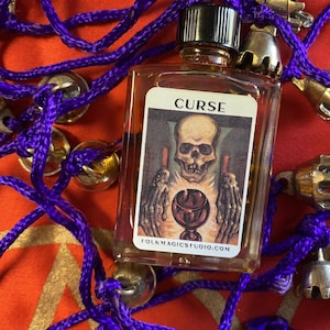 May include: A small glass bottle with a black cap and a label that reads "CURSE". The label features a skeletal figure holding a chalice. The bottle is surrounded by purple cords and gold bells.