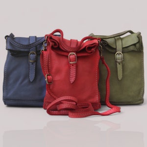 Puede incluir: Tres bolsos bandolera peque&ntilde;os en azul, rojo y verde oliva. Cada bolso cuenta con una solapa superior, una correa vertical con hebilla de metal en tono lat&oacute;n y una correa de hombro ajustable a juego con un peque&ntilde;o deslizador de metal.