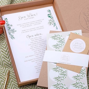 May include: A set of open when letters with a green leafy design. The letters are in a brown box with a white background. The text on the letters says "Open When..." and lists different reasons to open the letter, such as "You feel sad", "You miss me", "You feel happy", "You need motivating", "You miss the dog", "You need some love", "You need a laugh", "You miss home", "You are bored", "You want a trip down memory lane", "You are a mess", "You want to know how much I love you", "You need encouragement", "It's your birthday", "You feel like you need a hug", "When you're feeling down", "When you're feeling stressed", "When you're feeling lonely", "When you're feeling happy", "When you're feeling excited", "When you're feeling grateful", "When you're feeling loved", "When you're feeling inspired", "When you're feeling strong", "When you're feeling brave", "When you're feeling kind", "When you're feeling generous", "When you're feeling creative", "When you're feeling adventurous", "When you're feeling peaceful", "When you're feeling calm", "When you're feeling relaxed", "When you're feeling happy", "When you're feeling excited", "When you're feeling grateful", "When you're feeling loved", "When you're feeling inspired", "When you're feeling strong", "When you're feeling brave", "When you're feeling kind", "When you're feeling generous", "When you're feeling creative", "When you're feeling adventurous", "When you're feeling peaceful", "When you're feeling calm", "When you're feeling relaxed".
