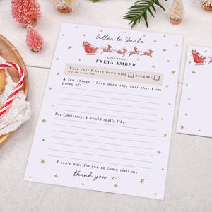 May include: A Christmas-themed letter to Santa Claus. The letter features a sleigh and reindeer illustration, with text that reads "letter to Santa" and "Love from Freya Amber". The letter is decorated with gold stars and a space to write.