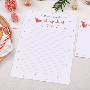 May include: White letter writing paper featuring a Santa Claus and reindeer illustration. The text "letter to Santa" and "Love from Freya Amber" are printed at the top. Gold stars are scattered around the edges.