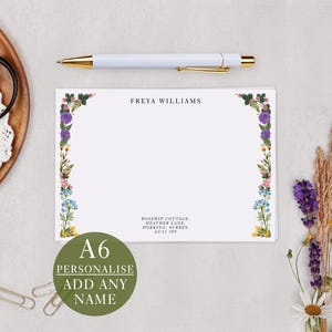 May include: A6 personalised stationery with floral border. The white card features the name "FREYA WILLIAMS" and address details. A white pen with gold accents rests above the card. A green circle with the text "PERSONALIZE ADD ANY NAME" is in the lower left corner.
