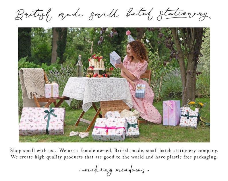 A woman in a pink dress is seated at a table with a cake and presents, surrounded by wrapped gifts and a wicker table.