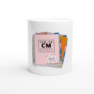 May include: White ceramic mug with a pink and white book with the text "ICD-10 CM EXPERT" and a cartoon illustration of a person wearing glasses. The book has a spiral binding and is stacked on top of other colorful books.