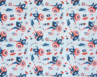 May include: A blue and red patterned fabric with a repeating design of a superhero figure holding a shield, stars, and fireworks. The background is a light blue color.