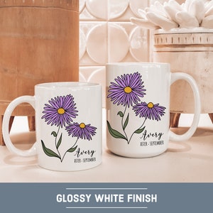 Puede incluir: Dos tazas de cer&aacute;mica blanca con un acabado brillante. Ambas tazas presentan un dise&ntilde;o de flores de aster p&uacute;rpura y el nombre "Avery" con el mes de nacimiento "septiembre".