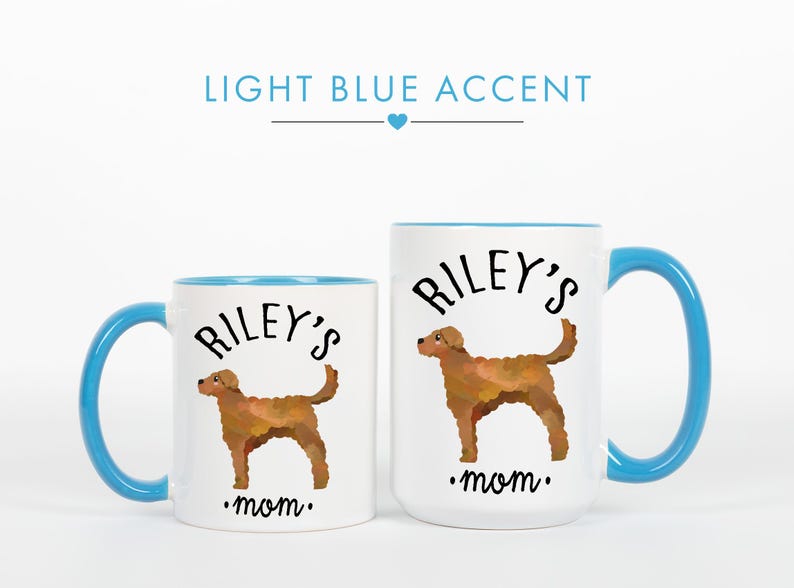 May include: Two white ceramic mugs with light blue accents. Each mug features a brown dog illustration, the text "Riley's" above the dog, and the word "mom" below. The handles and interior rims are light blue.